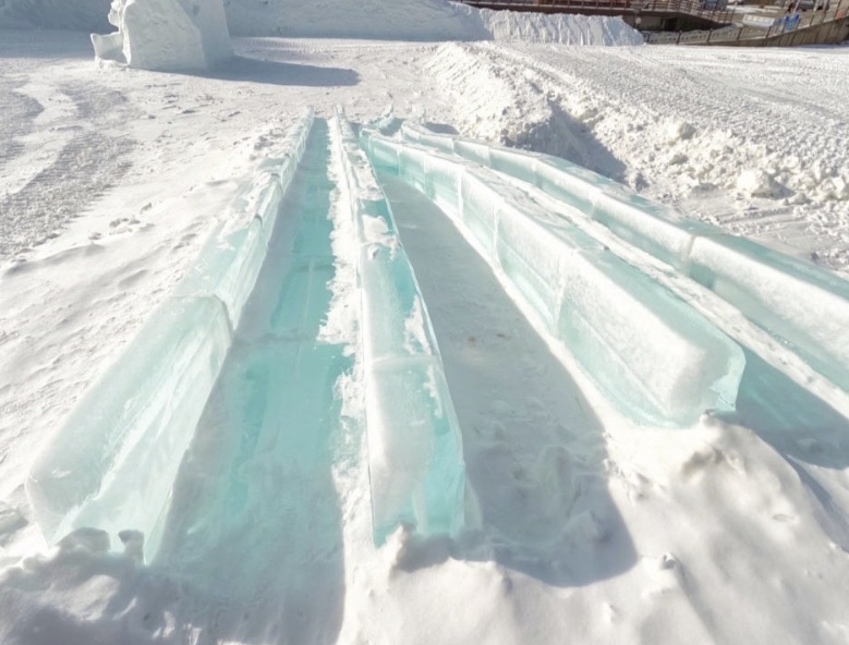 Ice slide lanes made of clear ice blocks at a winter festival in Gangwon Province, surrounded by snow-covered ground
