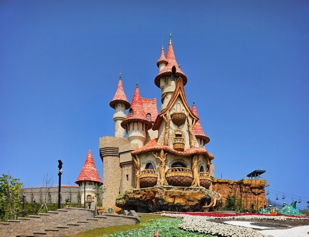 Fairy-tale castle at Lotte World Adventure Busan on a clear day, featuring detailed towers and gardens