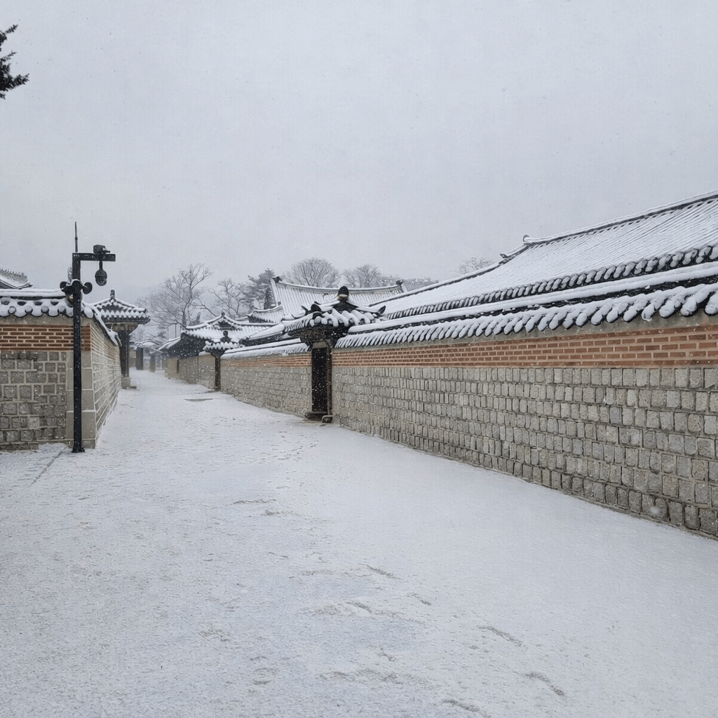 A quiet winter street in Seoul with traditional hanok walls covered in snow, showing the calm atmosphere of the city during winter